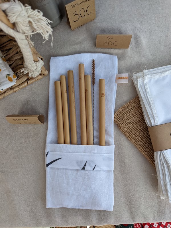 Sechs Bambustrinkhalme liegen in einer Baumwolltasche auf einem Produktetisch